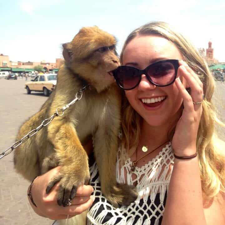 Jacqui, a young female traveler, taking a photo with a monkey in Marrakesh, Morocco.