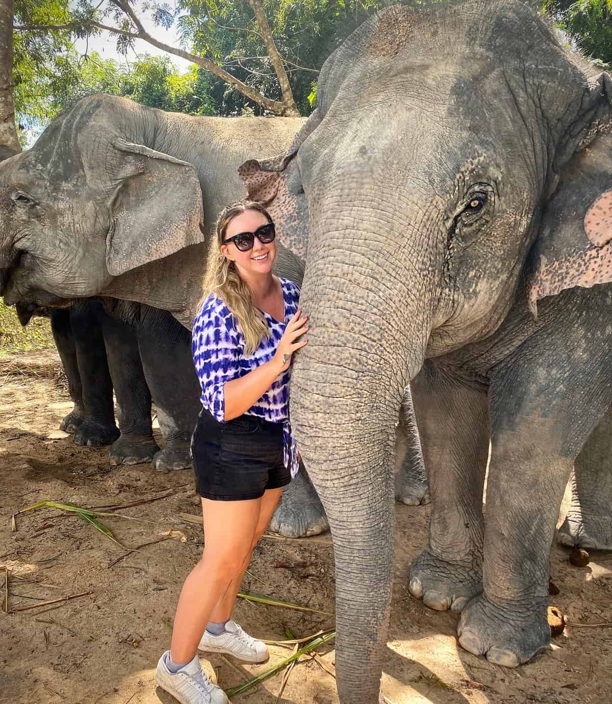 Jacqui standing and posing with elephants at the Angkor Wat elephant sanctuary in Cambodia.