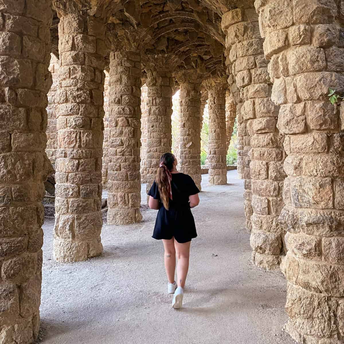 Jacqui, a young female traveler, walking through the old picturesque arches at Park Güell, a UNESCO World Heritage site, in Barcelona Spain.