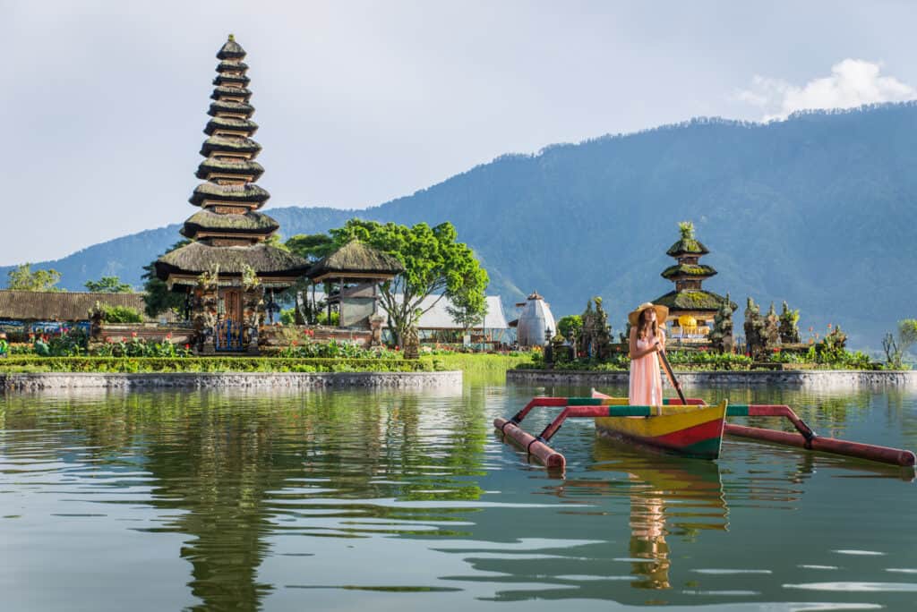 Young woman traveler paddling on a wooden boat in Bali, Indonesia